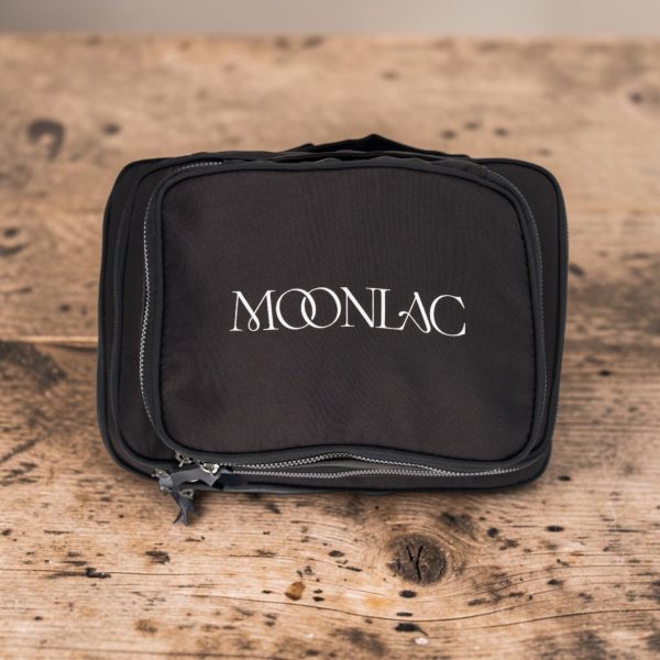 Cube de rangement valise noir vu de dessus, logo MOONLAC imprimé et fermeture éclair, sur une table en bois, MOONLAC chez Atelier Julac