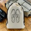 Sac à chaussures homme Classiques en coton écru Sac à chaussures homme en coton écru imprimé chaussures de ville à lacets, cordon noir, devant une valise, MOONLAC chez Atelier Julac