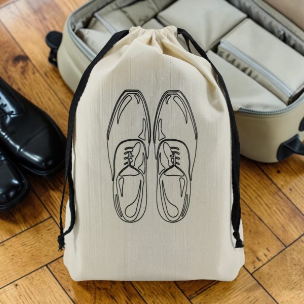 Sac à chaussures homme Classiques en coton écru Sac à chaussures homme en coton écru imprimé chaussures de ville à lacets, cordon noir, devant une valise, MOONLAC chez Atelier Julac