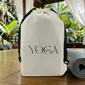 Sac de rangement sport Yoga en coton écru Sac de rangement sport en coton écru imprimé Yoga, cordon noir, à côté d'un tapis de yoga, MOONLAC chez Atelier Julac