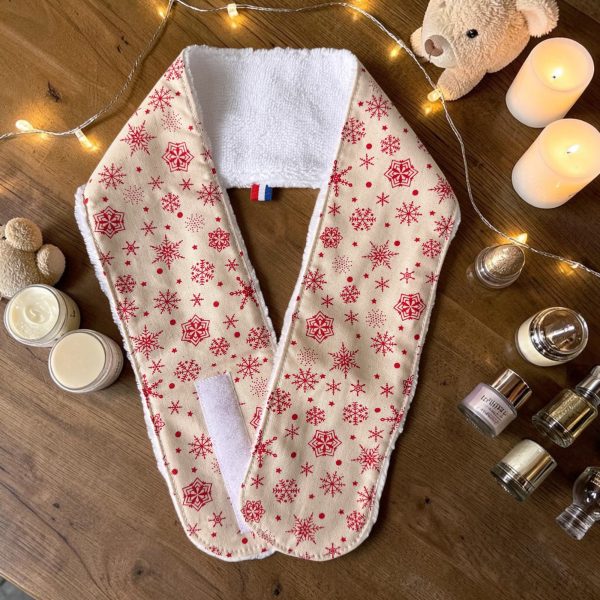 Bandeau de soins visage Noël beige flocons rouges fermeture scratch Bandeau de soins visage Noël beige à flocons rouges, avec fermeture scratch, posé avec des flacons de soins, cousu main par Atelier Julac