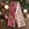 Bandeau de soins visage Noël rouge et beige chalet montagne Deux bandeaux de soins visage Noël, un rouge nordique et un beige à flocons rouges, posés avec une bougie, un peigne en bois et des branches de sapin, cousus main par Atelier Julac