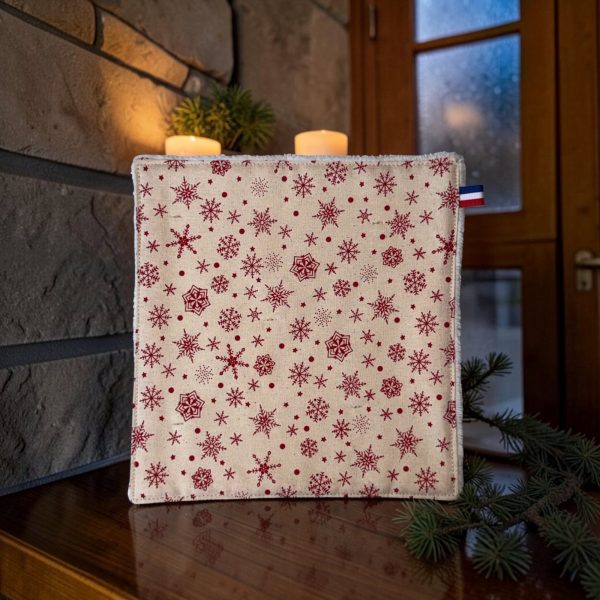 Serviette pour invités Noël montagne flocons de neige rouges Panière de serviettes pour invités Noël montagne, serviette en coton imprimé flocons de neige rouges sur fond écru, posée près de bougies et de branches de sapin - Atelier Julac